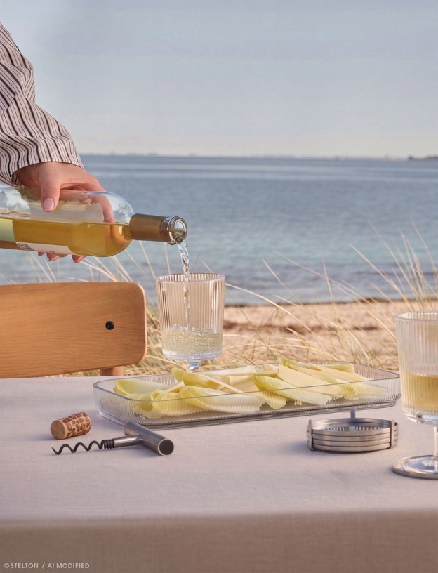 Stelton Pilastro Servierplatte aus Glas auf einem sommerlich gedeckten Tisch am Meer